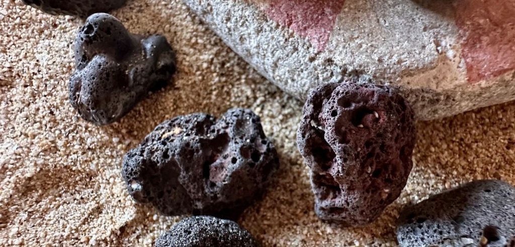 Fragmentos oscuros de posible escoria marina erosionados por el Mediterráneo.